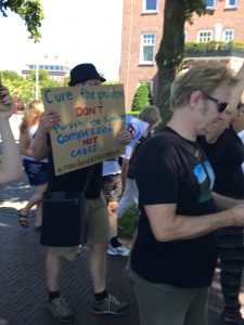 Man holding sign that says: "Cure the problem don't punish the symptom; Compassion not Cages."