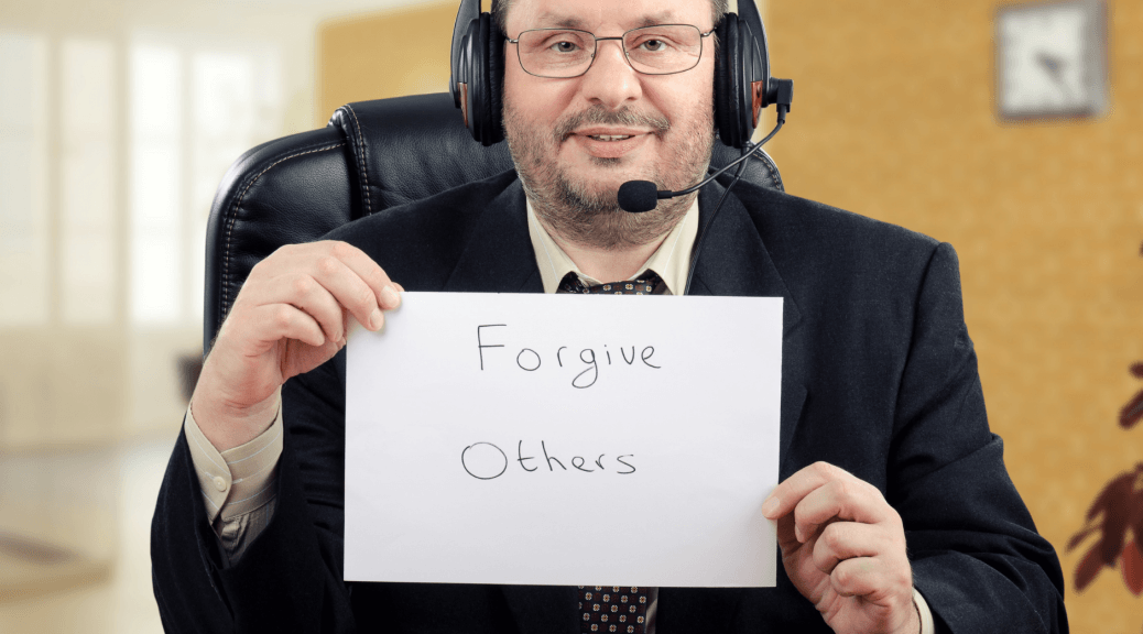 Man holds sign that reads "forgive others."