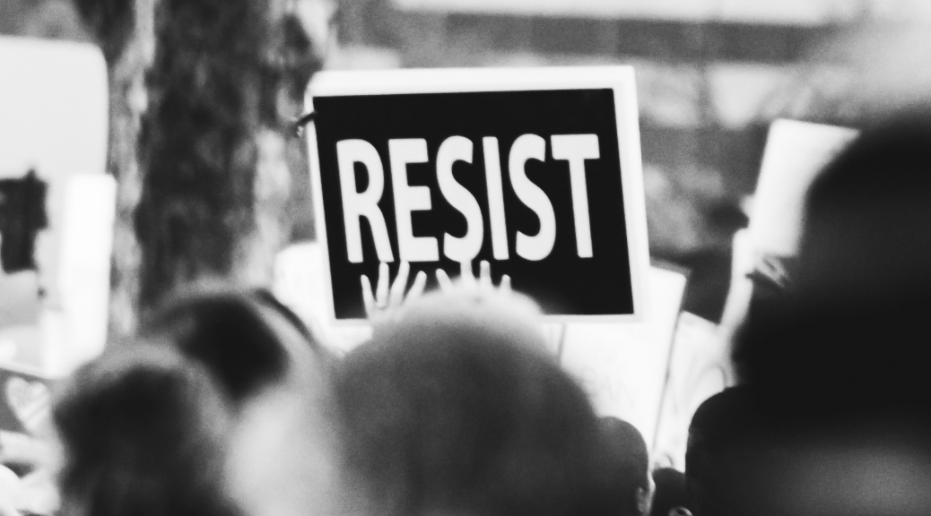 A picture of a sign that says Resist at a rally--introducing a piece about unhealthy and healthy law and order theologies