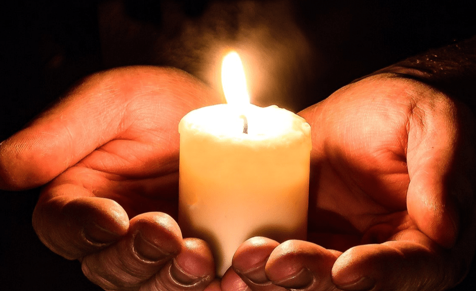 A lit candle in hands, introducing an article about non-toxic positivity