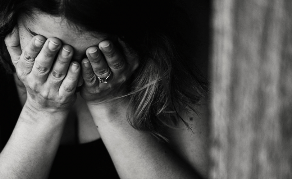 A picture of a person with head in hands introducing an article about a year of pandemic trauma